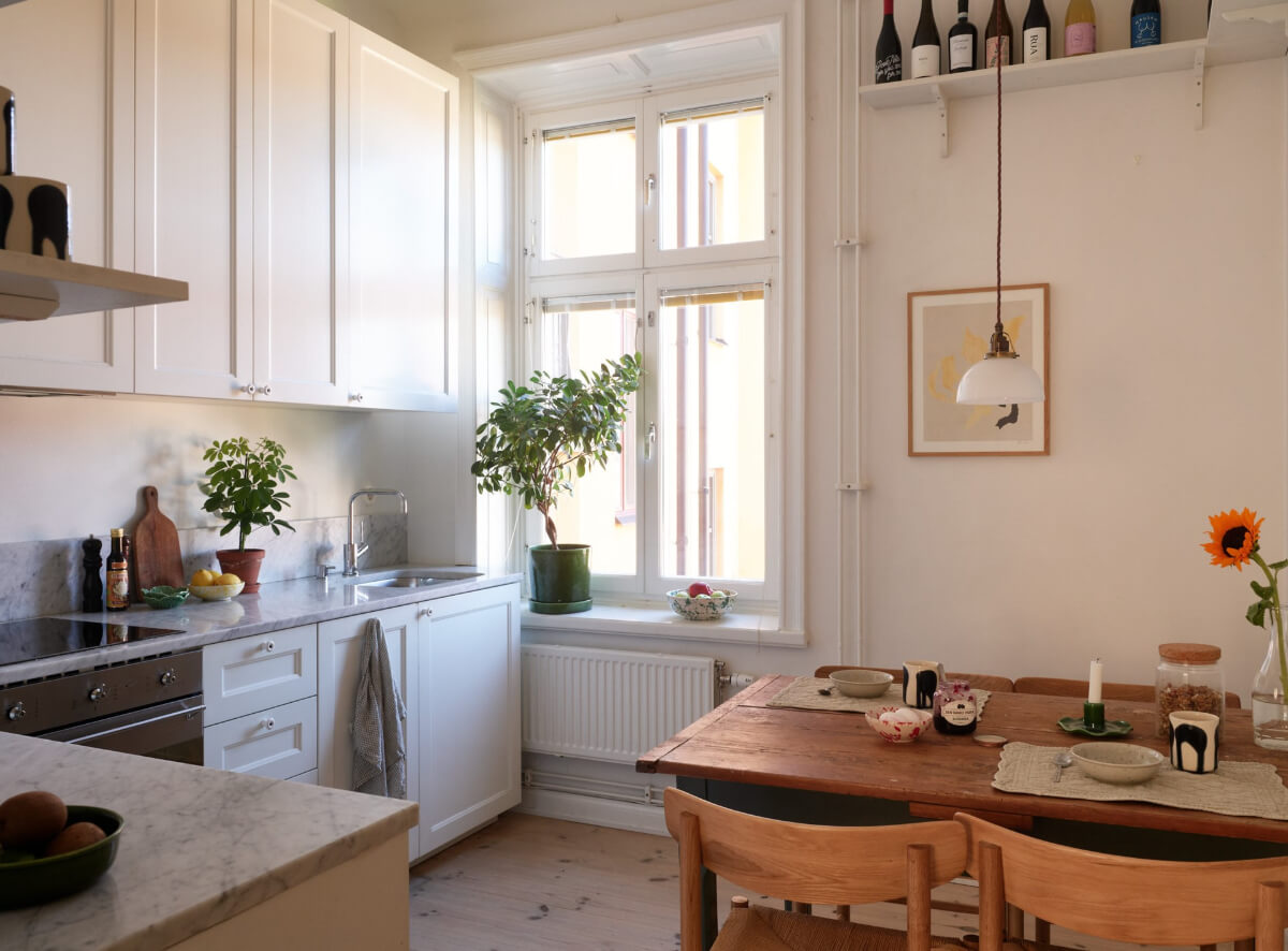 A Light-Filled Stockholm Apartment with Bright Color Pops 17 white kitchen wooden dining table