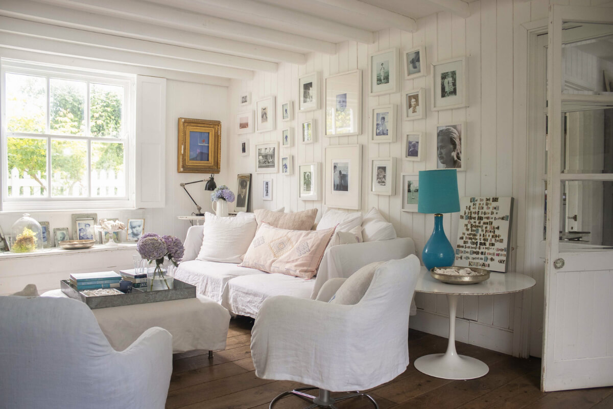 A Bright New England-Style Home with a Lush Garden 8 white wooden living room gallery wall