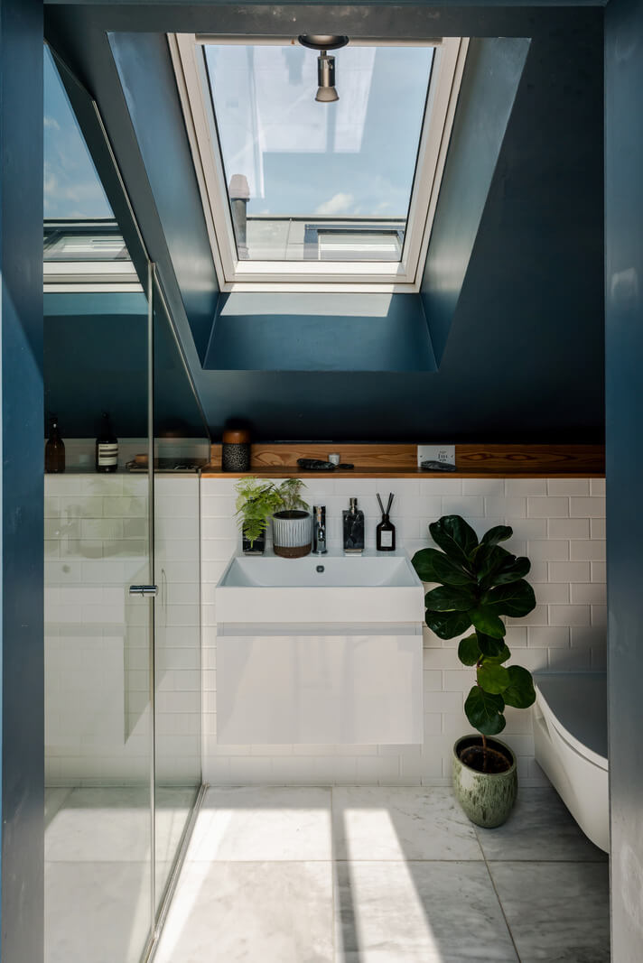 A High-Pitched Ceiling In a Light London Duplex Apartment 18 bathroom dark blue slanted walls