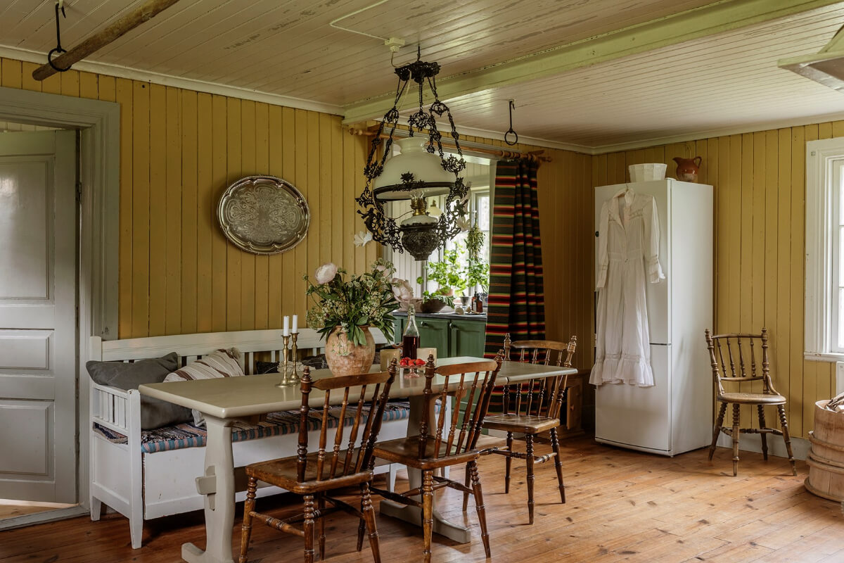 A Beautifully Preserved Historic Country House in Sweden 12 dining room with seating bench ochre yellow paneling