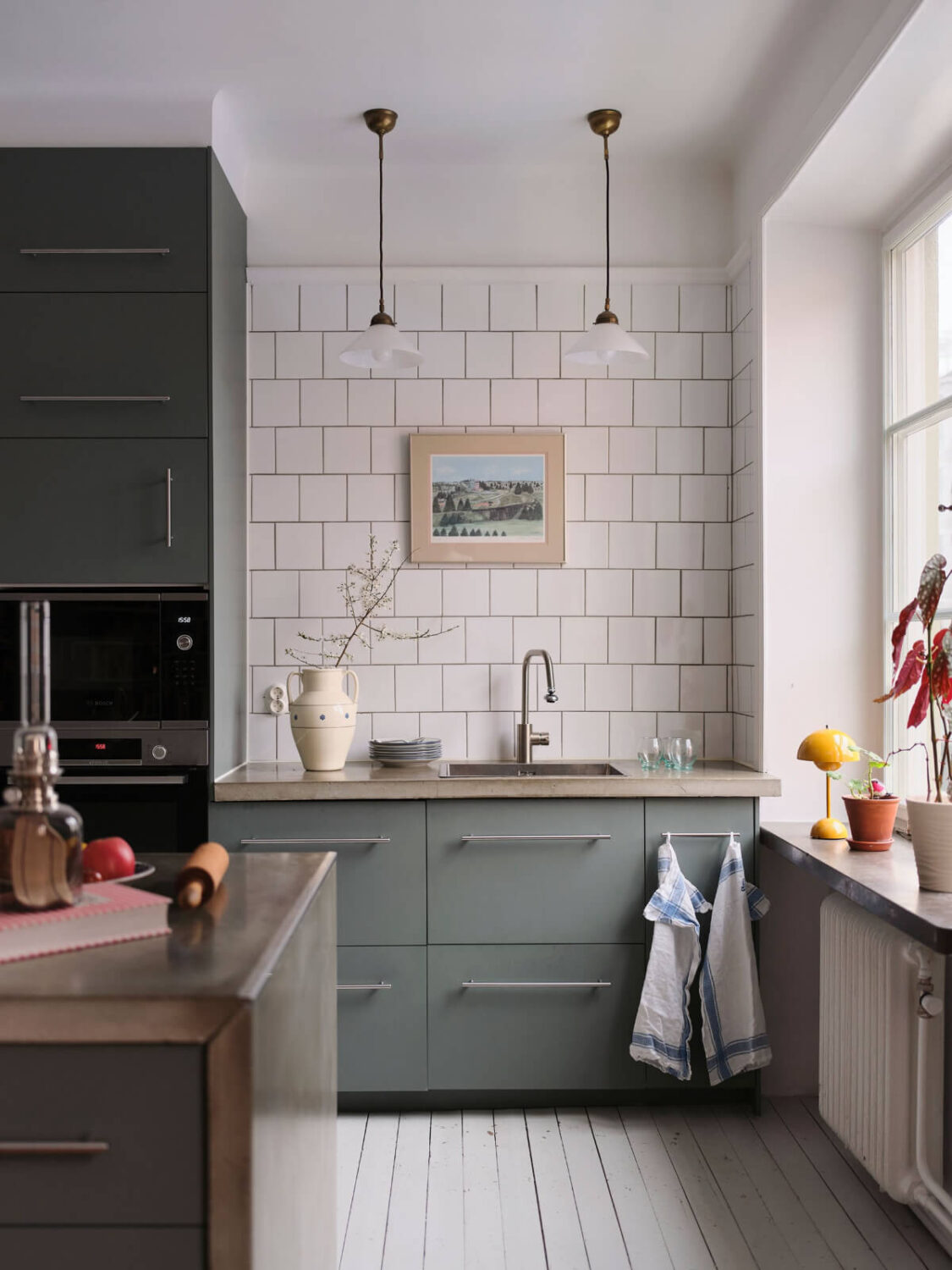 An Early 20th Century Apartment with a Muted Green Kitchen 4 green cabinets concrete countertop white backsplash tiles