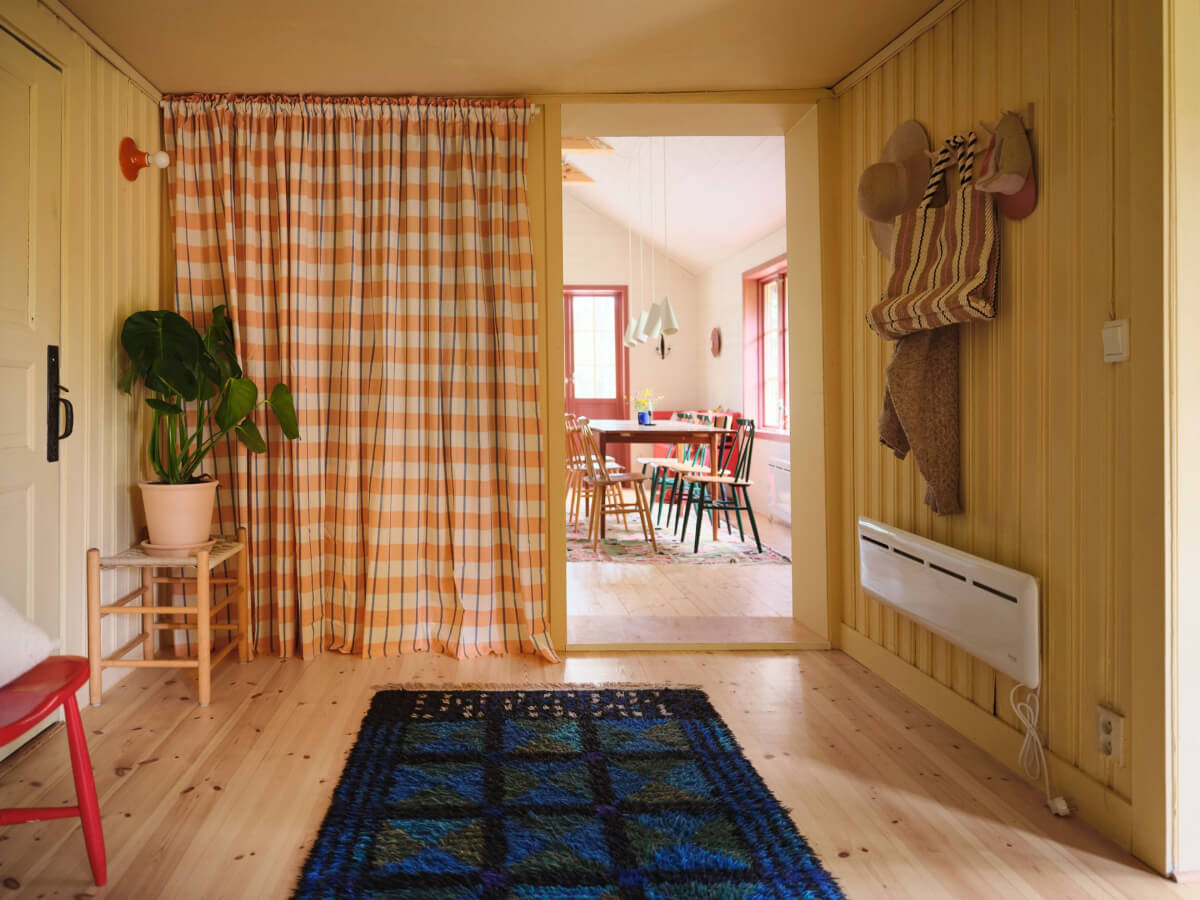 A Charming, Extended 19th-Century Log House in Sweden 14 yellow hallway storage behind patterned curtains
