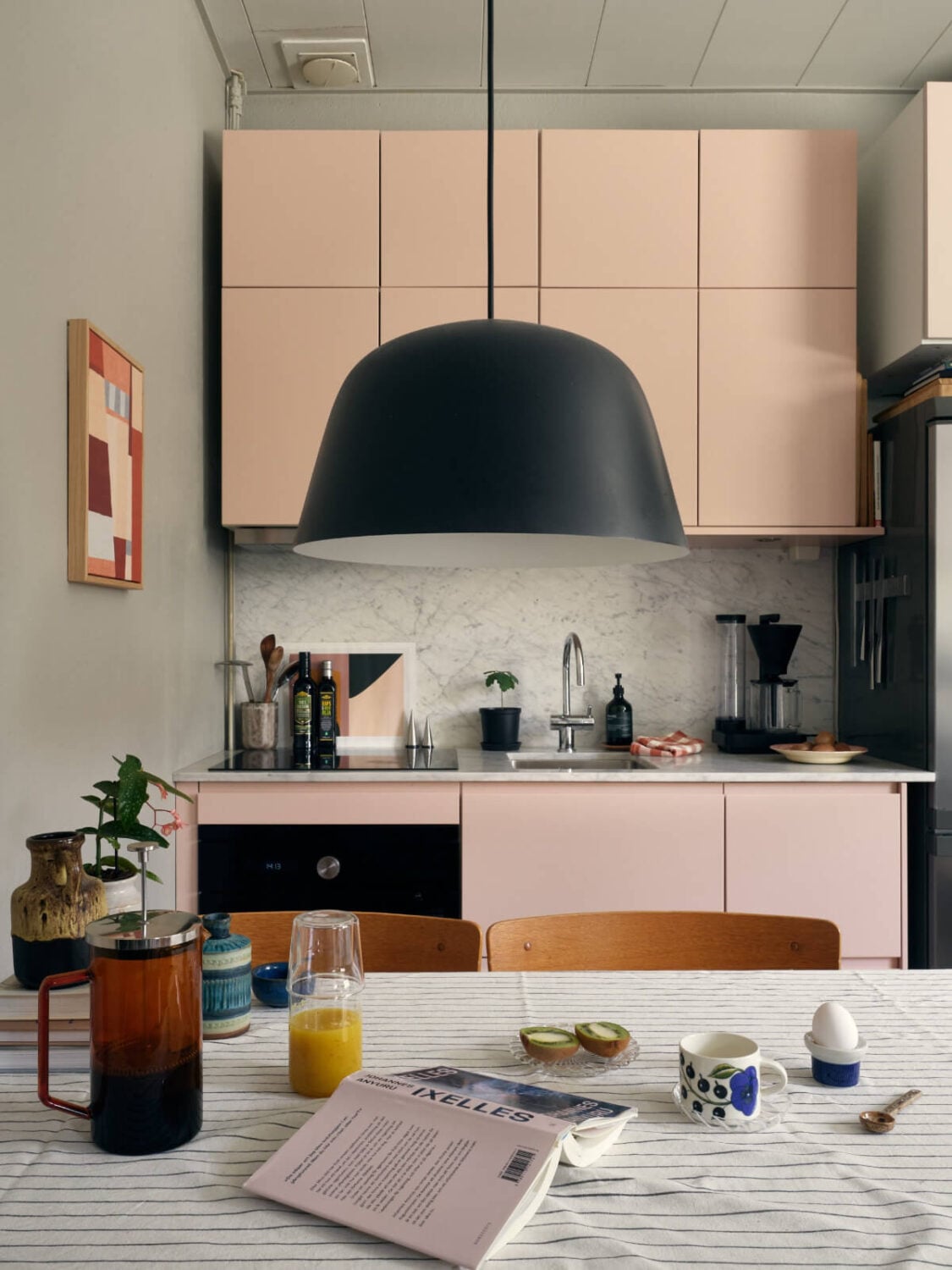 A Tiny Apartment with a Semi-Open Floorplan and a Pink Kitchen 8 light pink kitchen and dining table