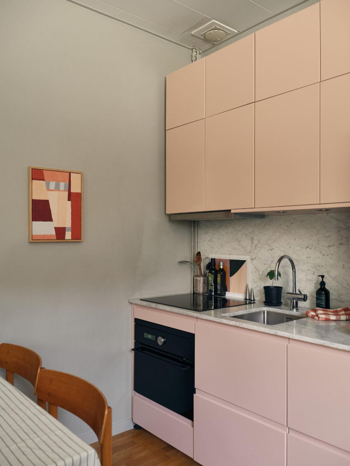 A Tiny Apartment with a Semi-Open Floorplan and a Pink Kitchen 9 light pink kitchen cabinets marble countertop