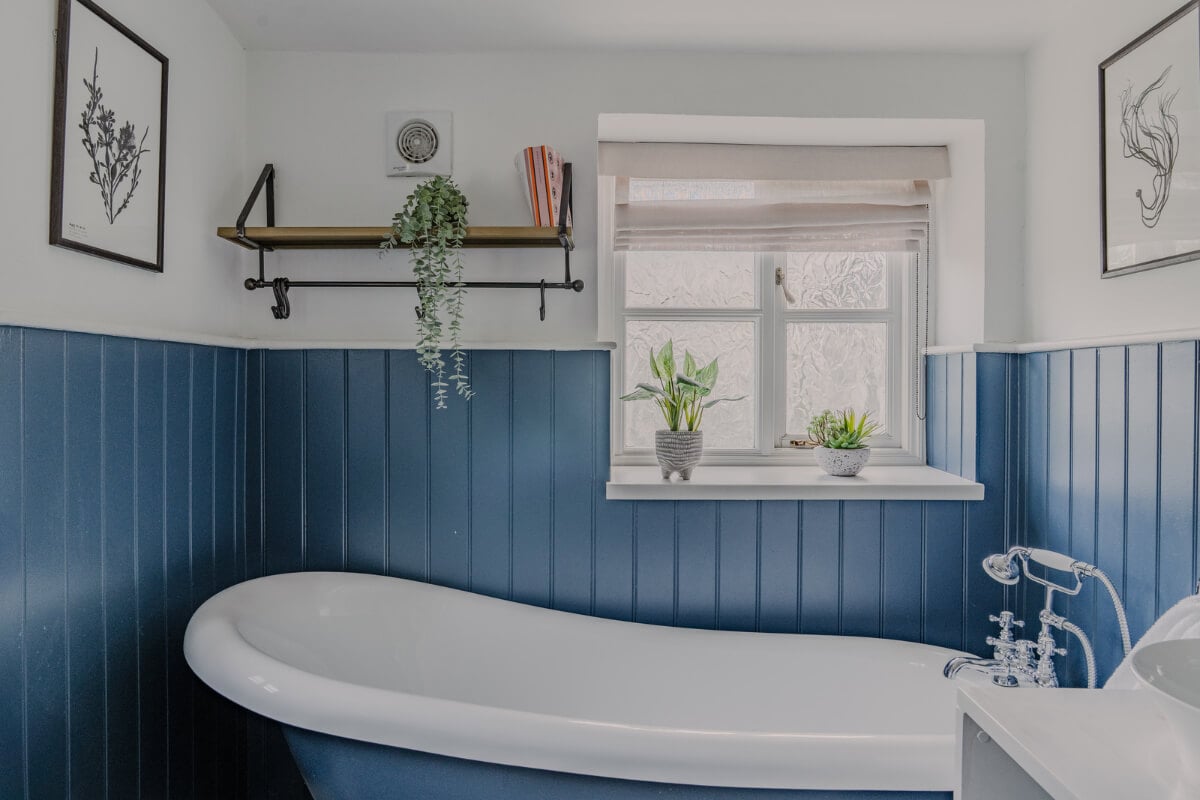 A Stone English Cottage with a Blue and Pink Kitchen 20 bathroom blue paneling and freestanding bath