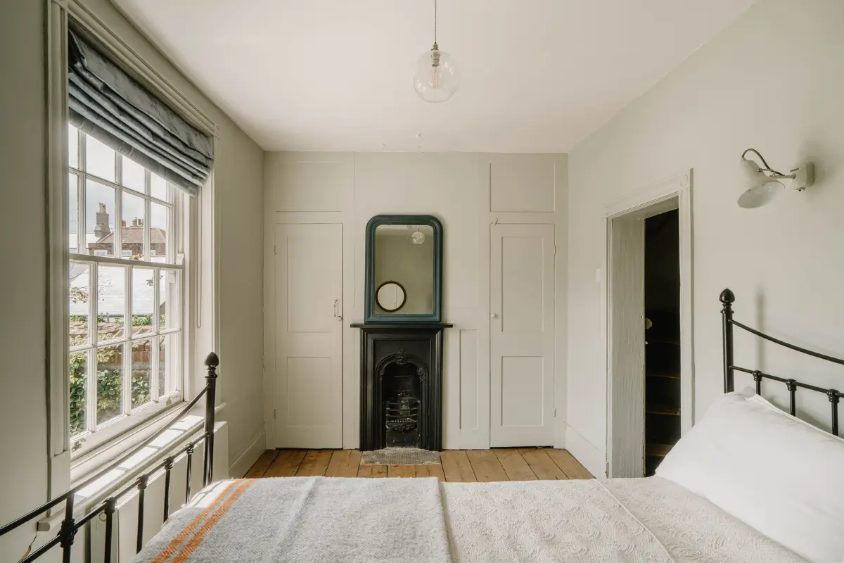 A 17th-Century Home with Original Elements in an English Seaside Town 12 bedroom with small fireplace and built-in wardrobes