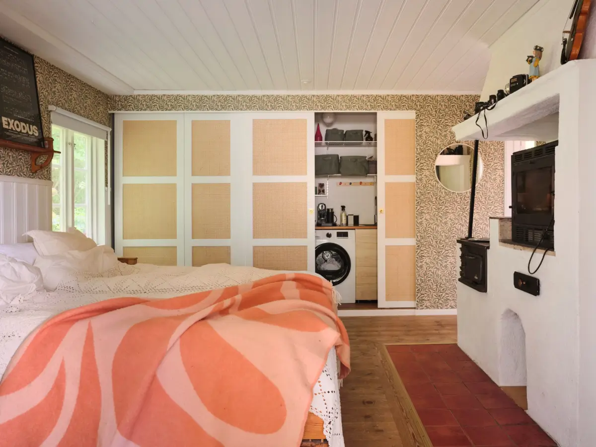 A Colorful Family Home in an Old Gardener's Cottage in Sweden 27 bedroom with washing machine behind cane doors