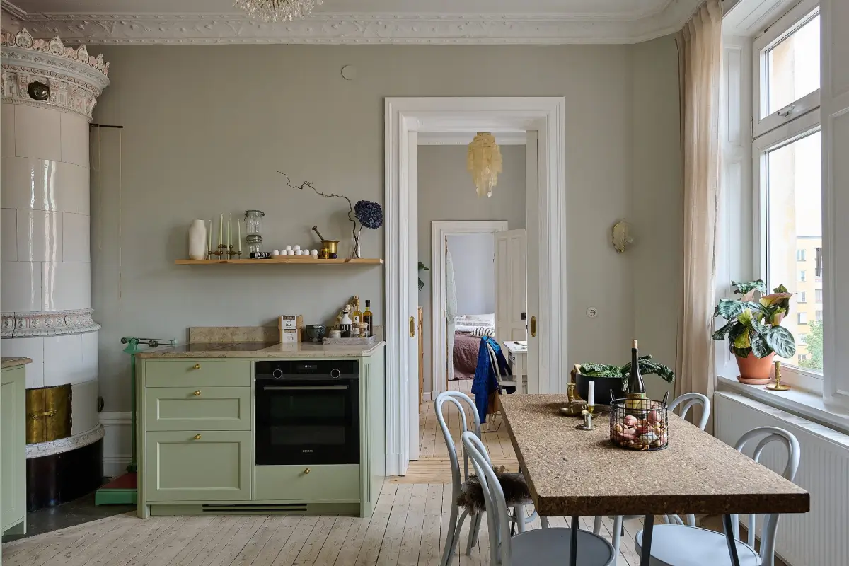 A Classic Stockholm Family Apartment with a Separate Studio 9 green kitchen with fireplace and cork table