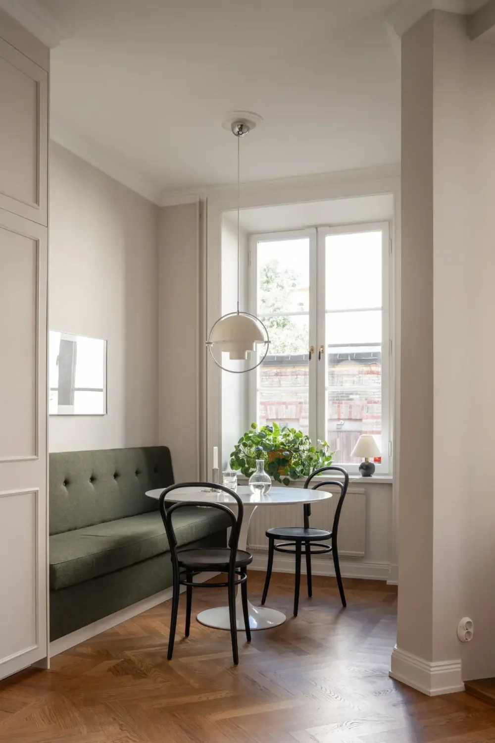 Arched Windows and Design Classics in a 19th Century Apartment 9 kitchen dining nook round table green bench