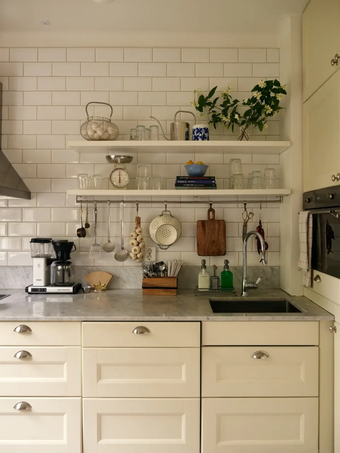 A Muted Color Palette in a Cozy 1920s Apartment in Stockholm 9 kitchen with white tiles and shelves nordroom