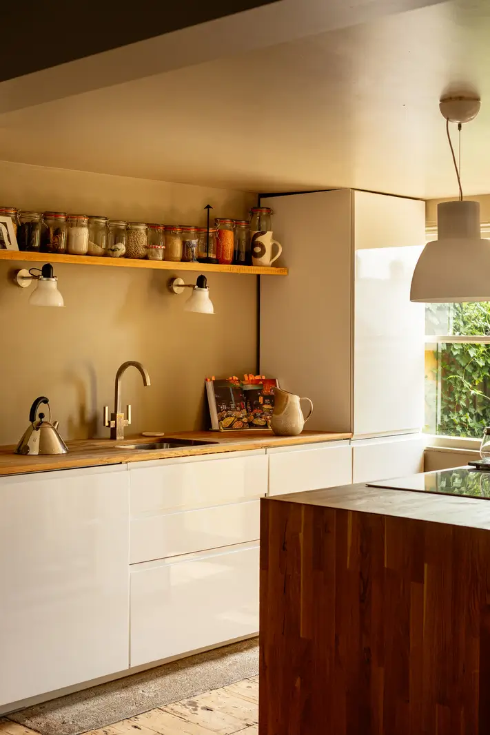 A Muted Color Palette and Original Details in a Victorian Terrace House 3 white kitchen cabinets wooden countertop display shelf