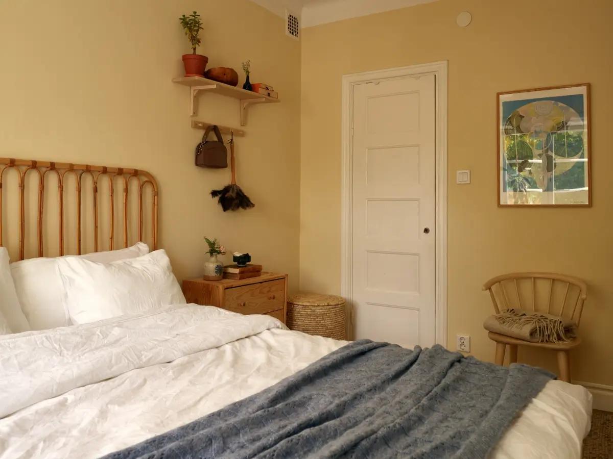 A Muted Color Palette in a Cozy 1920s Apartment in Stockholm 15 yellow-beige bedroom rattan headboard nordroom
