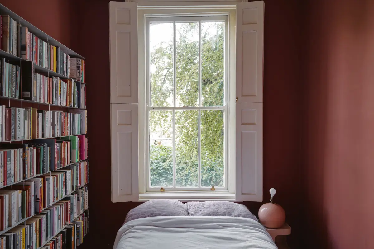 PPG & Glidden Color of the Year 2026: Warm Mahogany 6 dark red color-drenched bedroom bookshelves bed under window nordroom