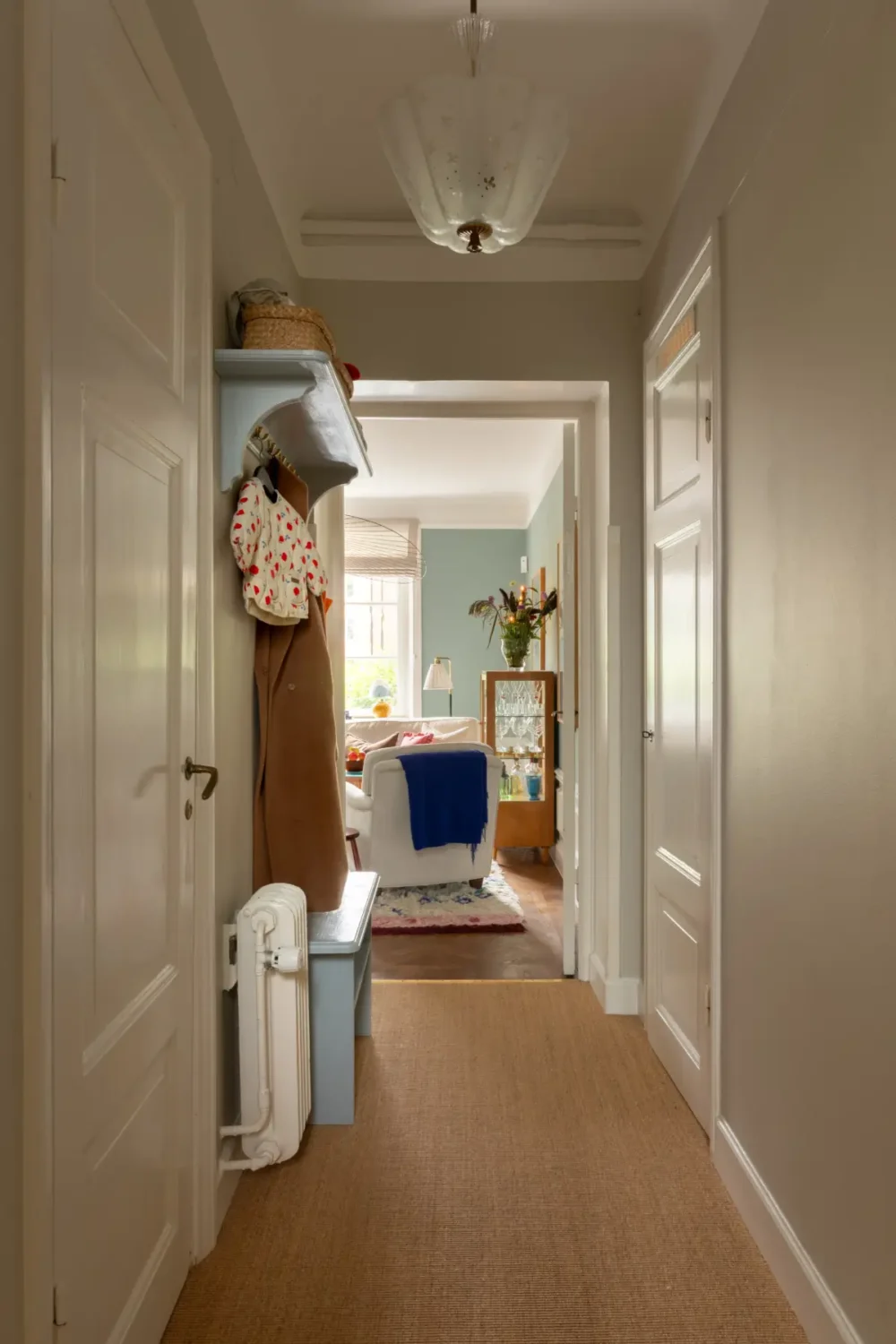 A Warm Color Palette in a Cozy 1920s Apartment in Stockholm 29 hall sisal carpet blue hat shelf and bench