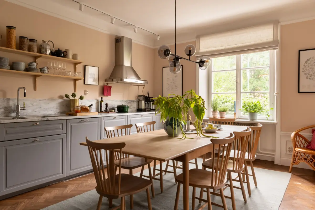 A Warm Color Palette in a Cozy 1920s Apartment in Stockholm 1 kitchen light terracotta walls gray cabinets large dining table