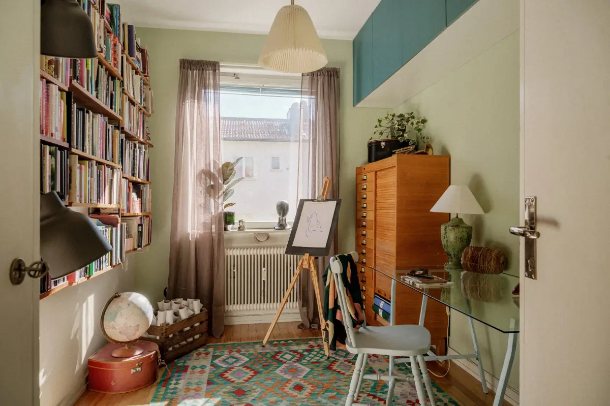 Green Tones and Period Elements in a 1940s Apartment 13 home office bookshelves glass desk colorful rug