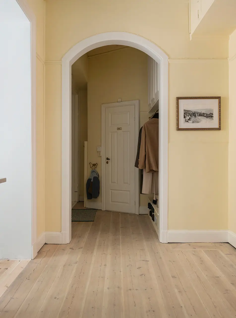 A Stylish Beige Apartment with a Light Blue Kitchen 29 pastel yellow hall arched doorway