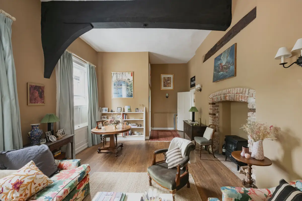A Charming English Cottage with a Sage-Green Kitchen 4 spacious cottage living room warm neutral walls brick fireplace