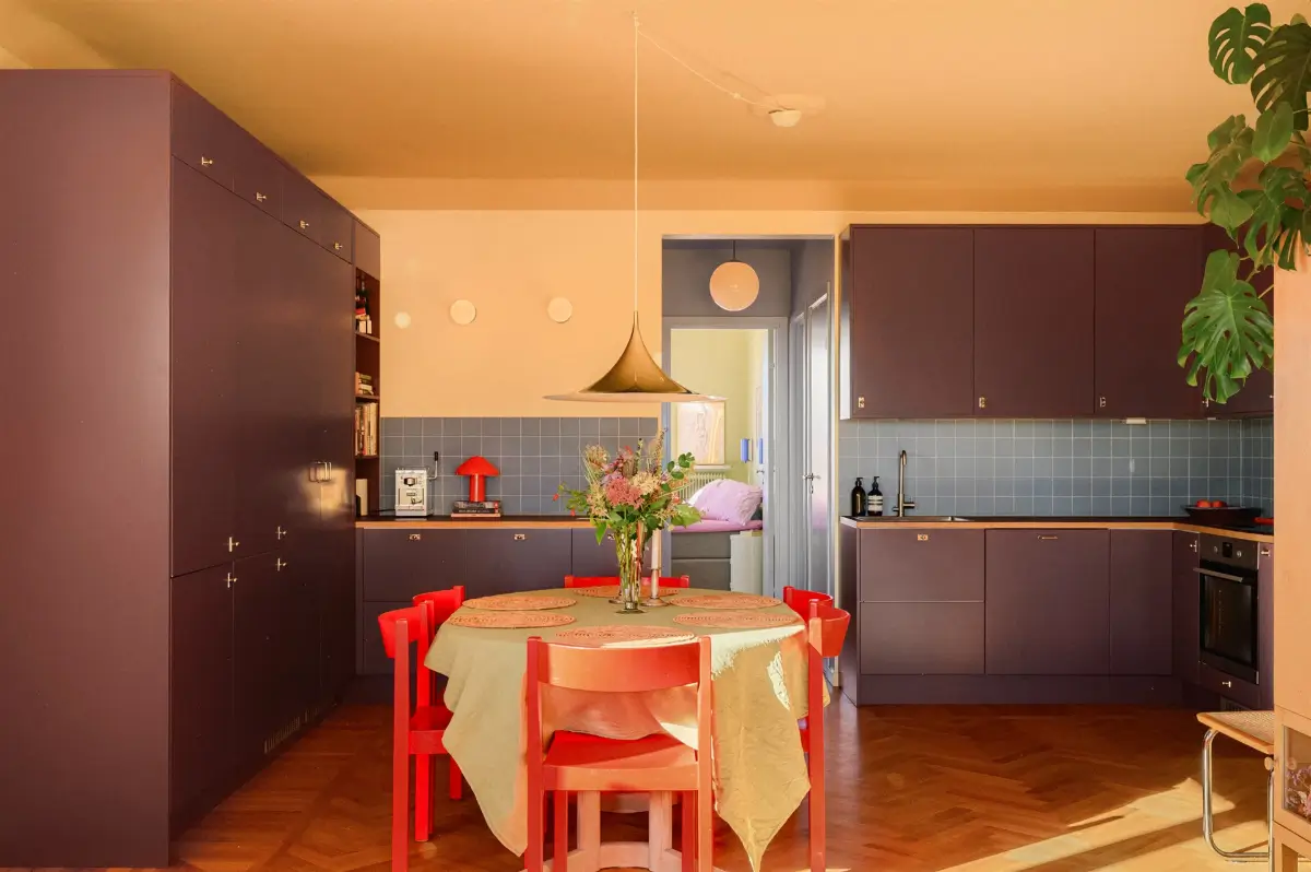 A Colorful Stockholm Family Apartment with Views of the Lake 11 spacious kitchen plum-colored cabinets dining table with red chairs nordroom