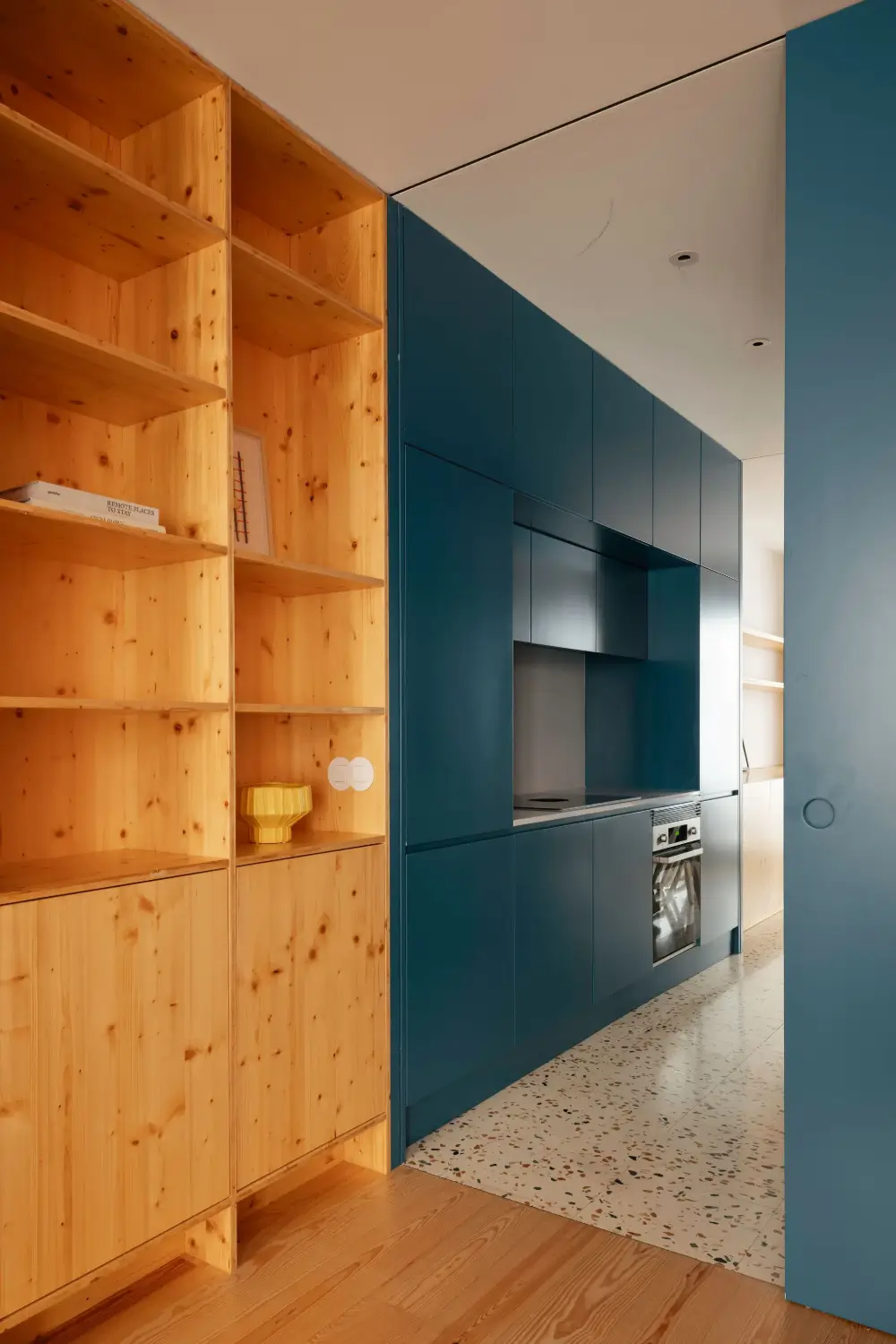 The 2027 Color of the Year Prediction: A Shift Toward More Expressive Colors? 4 dark-blue-kitchen-terrazzo-floor-wooden-bookshelves-nordroom