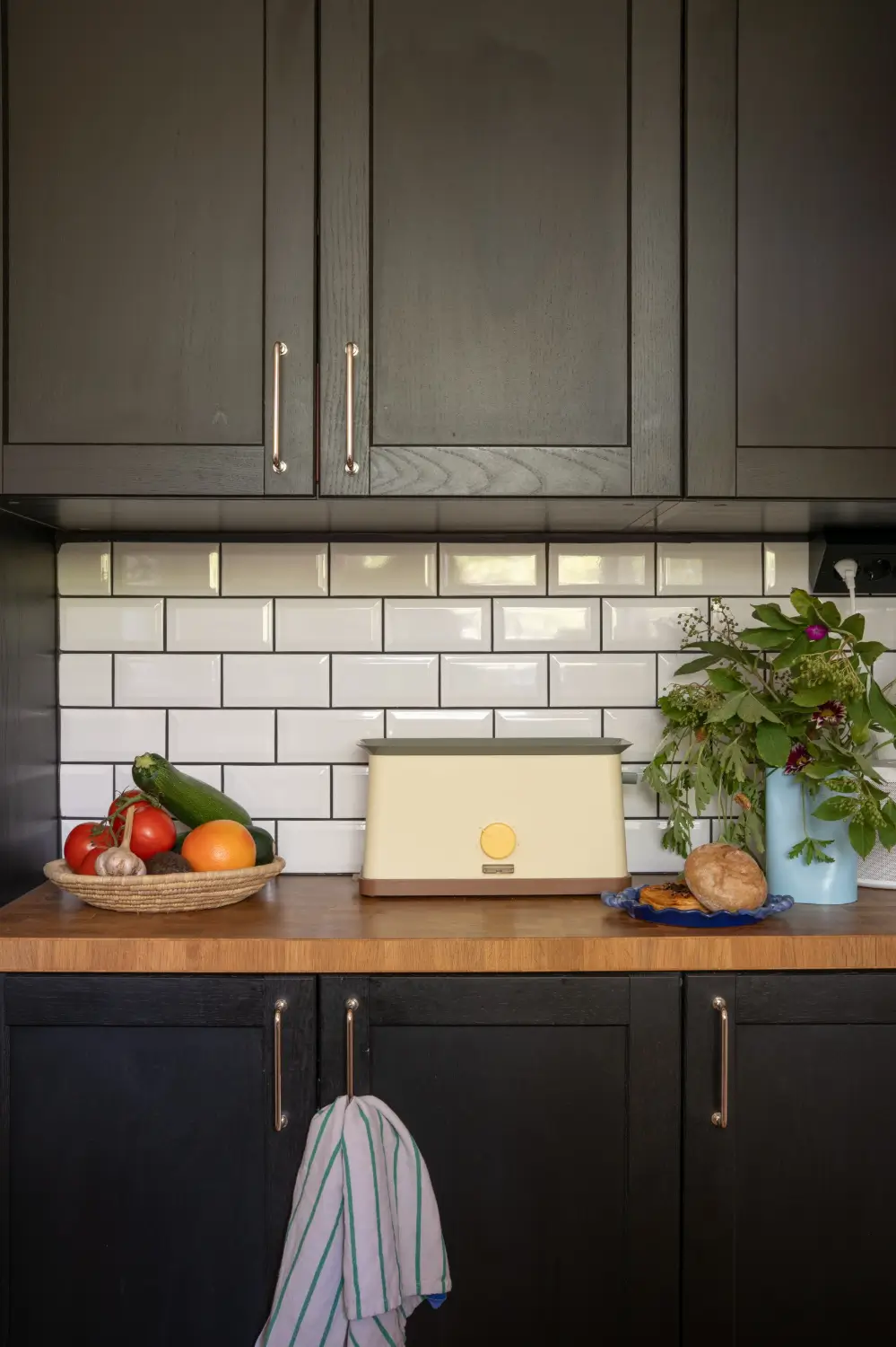 Cheerful Colors in a Small & Light 1940s Apartment in Stockholm 26 dark-gray-kitchen-cabinets-wooden-top-white-backsplash-tiles-nordroom